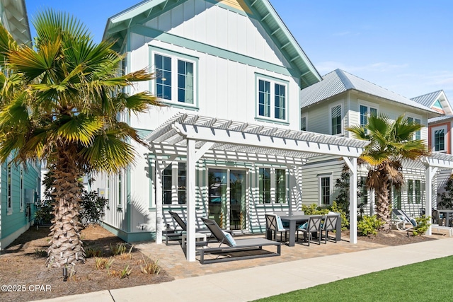 rear view of property featuring board and batten siding, a patio area, and a pergola