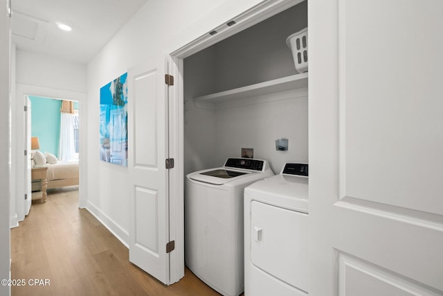 laundry room with light wood finished floors, laundry area, washing machine and dryer, and attic access