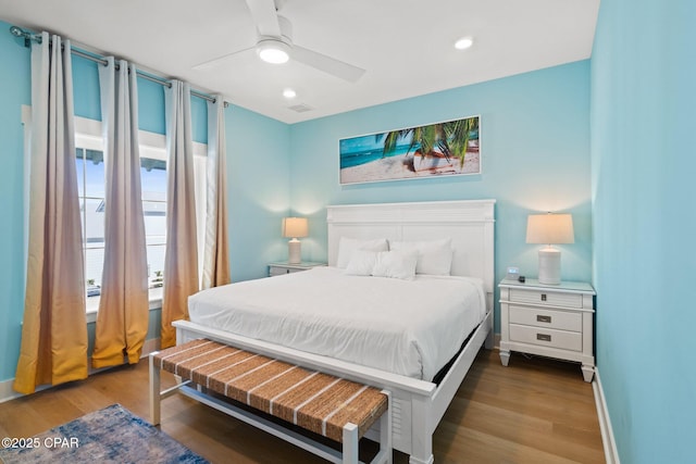 bedroom with ceiling fan, wood finished floors, visible vents, and baseboards