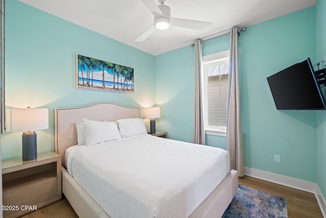 bedroom featuring baseboards, wood finished floors, and a ceiling fan