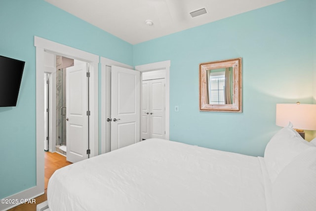 bedroom with visible vents, baseboards, and wood finished floors