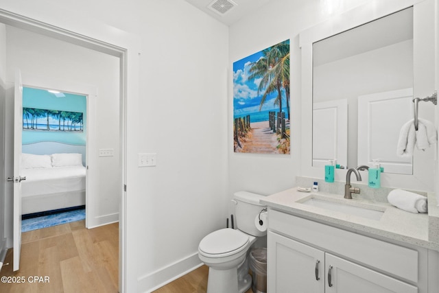 bathroom with visible vents, toilet, wood finished floors, baseboards, and vanity