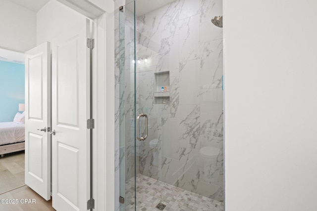 bathroom featuring a marble finish shower, connected bathroom, and wood finished floors