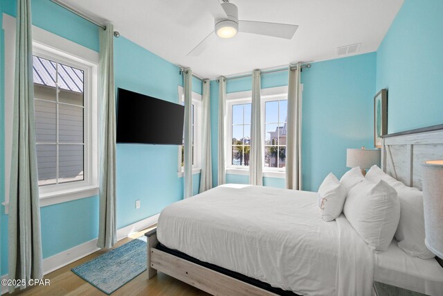 bedroom featuring ceiling fan, wood finished floors, visible vents, and baseboards