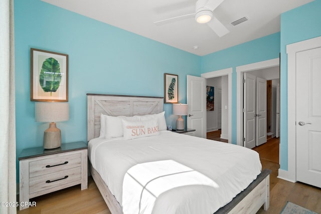 bedroom with wood finished floors, visible vents, and ceiling fan