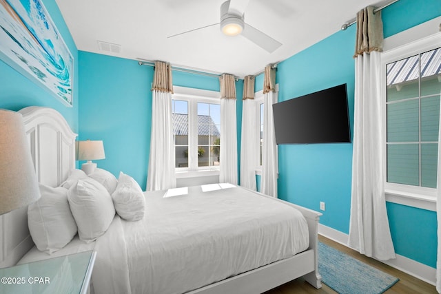 bedroom with baseboards, wood finished floors, visible vents, and ceiling fan