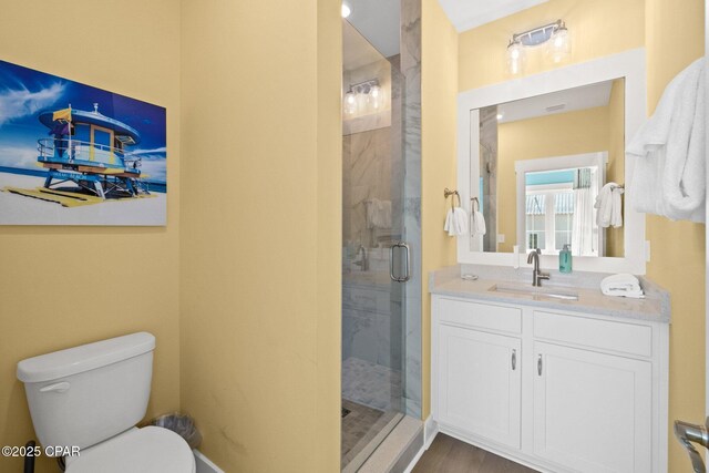 full bath featuring vanity, toilet, wood finished floors, and a shower stall