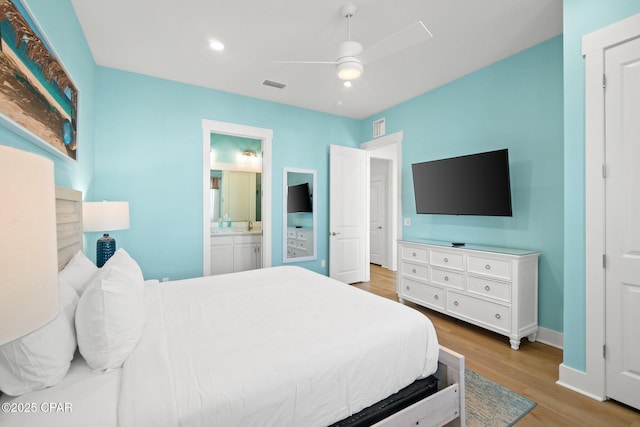 bedroom featuring ceiling fan, wood finished floors, visible vents, and connected bathroom