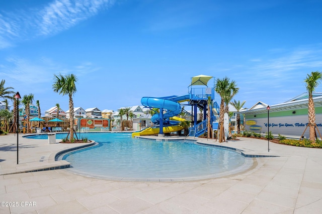 pool featuring a patio, a water slide, and a water play area