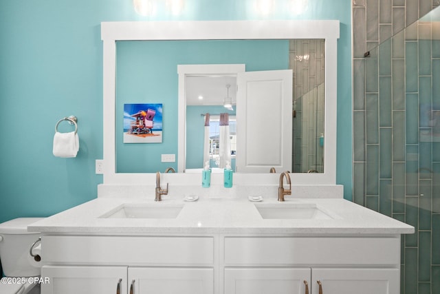 bathroom featuring double vanity, a tile shower, and a sink