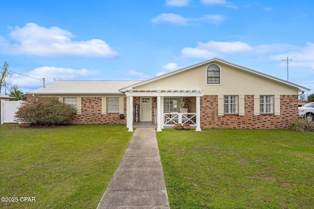 view of front of house with metal roof, brick siding, a front lawn, and fence