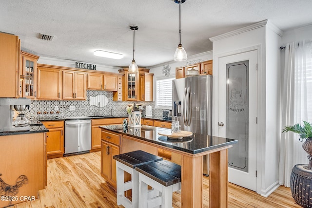 kitchen with stainless steel appliances, visible vents, light wood-style flooring, and a center island