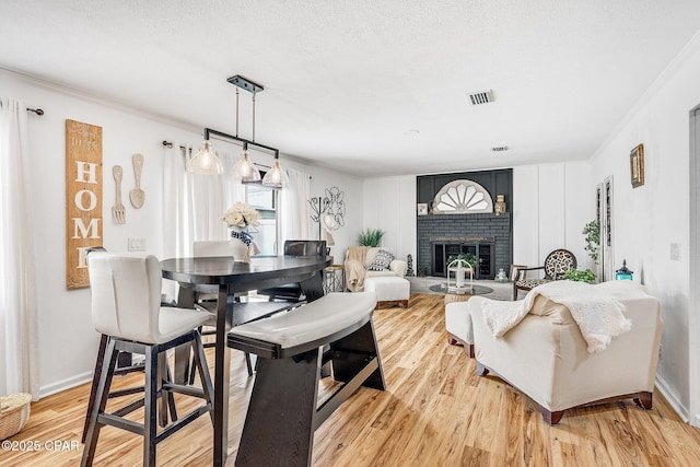 dining room featuring visible vents, a fireplace, baseboards, and light wood-style floors