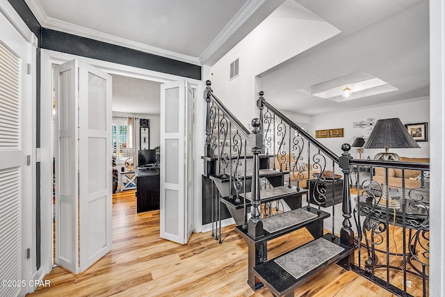 stairway with visible vents, ornamental molding, baseboards, and wood finished floors