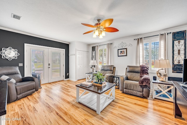 living area with french doors, visible vents, wood finished floors, and ornamental molding