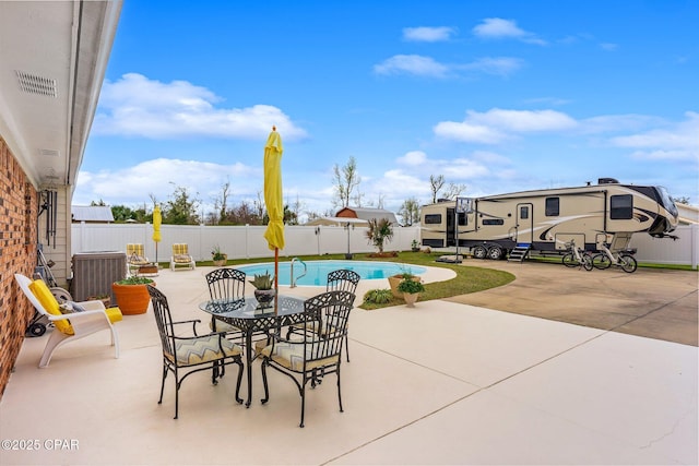 view of patio with a fenced backyard, outdoor dining space, a fenced in pool, and central AC