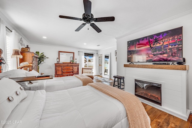 bedroom featuring ornamental molding, ceiling fan, a glass covered fireplace, wood finished floors, and access to exterior