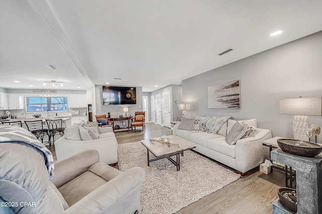 living area with recessed lighting, visible vents, and light wood-style floors