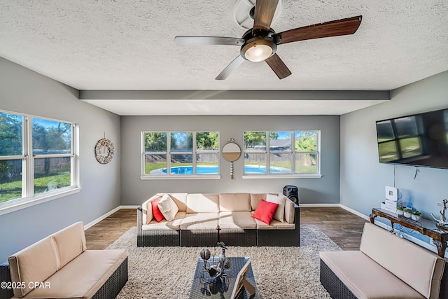 living room with ceiling fan, a textured ceiling, and wood finished floors