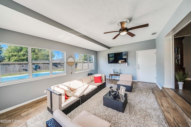 living area featuring baseboards, a textured ceiling, wood finished floors, and a ceiling fan