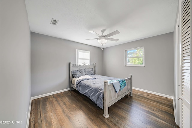 bedroom featuring dark wood finished floors, visible vents, and multiple windows