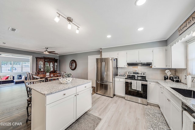 kitchen with visible vents, a center island, under cabinet range hood, light wood-type flooring, and appliances with stainless steel finishes