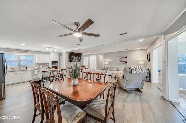 dining space with light wood finished floors, visible vents, baseboards, and a ceiling fan