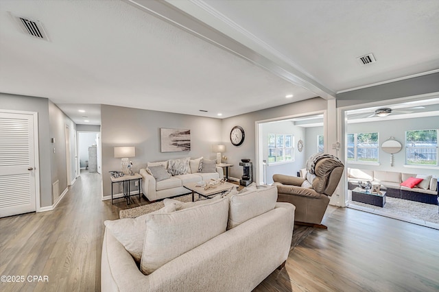 living area featuring beam ceiling, visible vents, baseboards, and wood finished floors