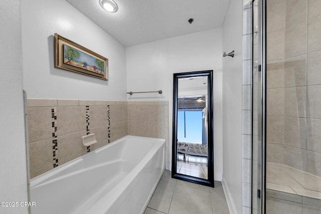 full bathroom featuring tile patterned floors, a textured ceiling, a bath, and a shower stall