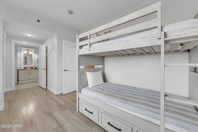 bedroom with light wood finished floors, baseboards, and a sink