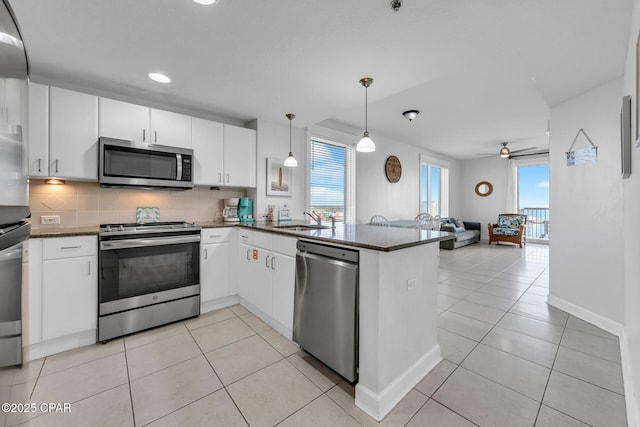 kitchen featuring a peninsula, a sink, appliances with stainless steel finishes, tasteful backsplash, and open floor plan