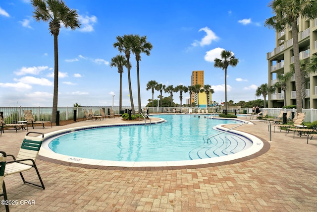 community pool with a patio area and fence