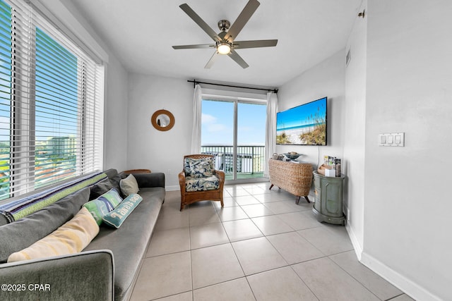 living room featuring a ceiling fan, light tile patterned flooring, a healthy amount of sunlight, and baseboards