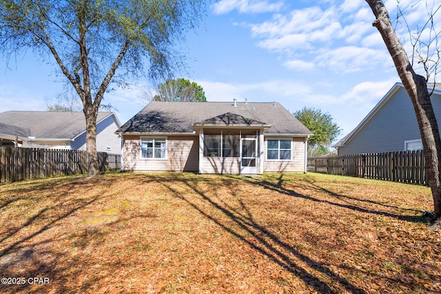 rear view of house with a yard, a shingled roof, a fenced backyard, and a sunroom