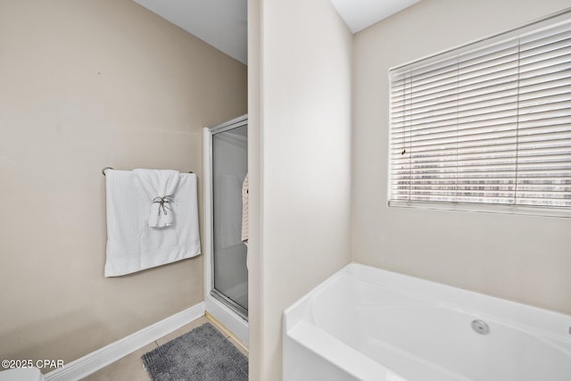 bathroom with a bath, a shower stall, tile patterned floors, and baseboards