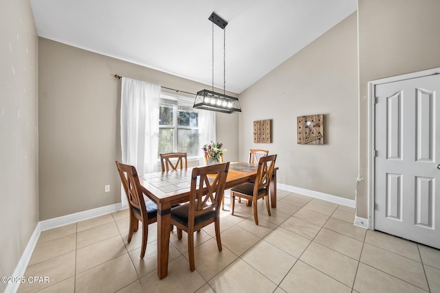 dining space with light tile patterned floors, baseboards, and lofted ceiling