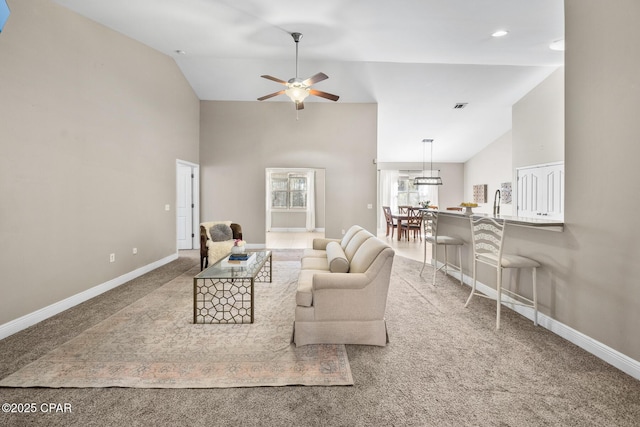 carpeted living area with high vaulted ceiling, baseboards, and ceiling fan