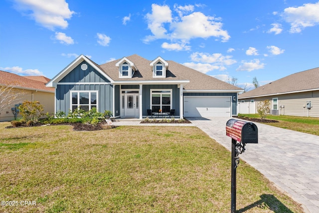 view of front of home with a front yard, decorative driveway, board and batten siding, and an attached garage