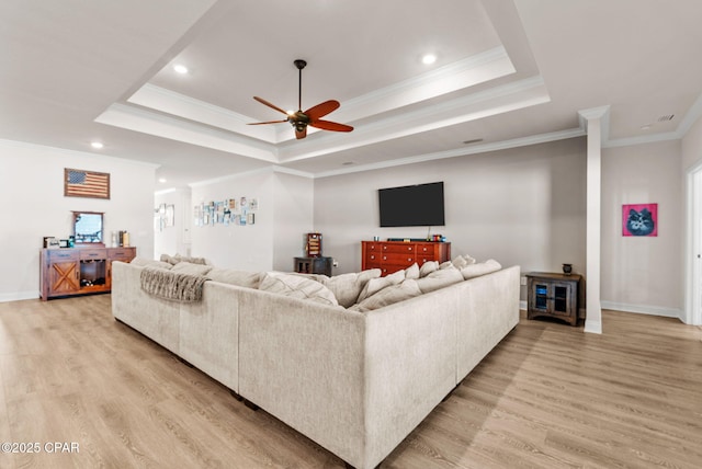 living area with a tray ceiling, baseboards, light wood-type flooring, and ceiling fan