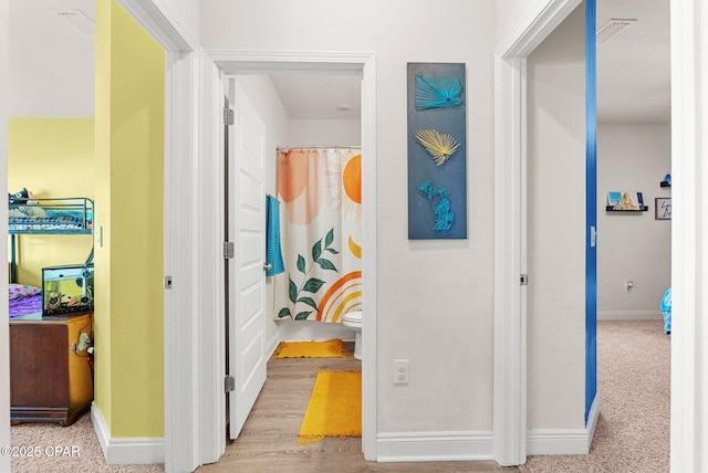 hallway featuring carpet flooring, visible vents, and baseboards