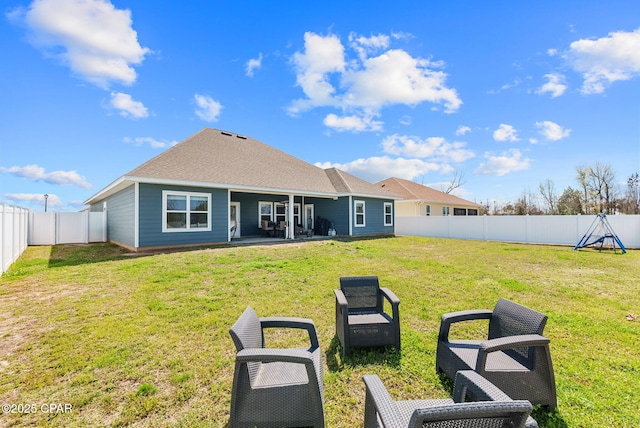 rear view of house featuring a patio area, a fenced backyard, a lawn, and roof with shingles