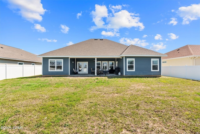 back of house with a fenced backyard, a patio area, a yard, and roof with shingles