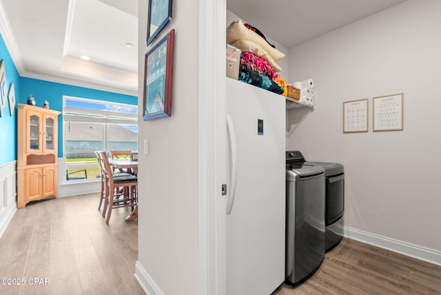 washroom featuring baseboards, light wood finished floors, laundry area, separate washer and dryer, and crown molding