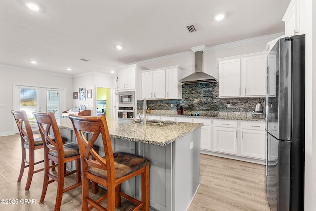 kitchen with crown molding, appliances with stainless steel finishes, wall chimney exhaust hood, and a sink