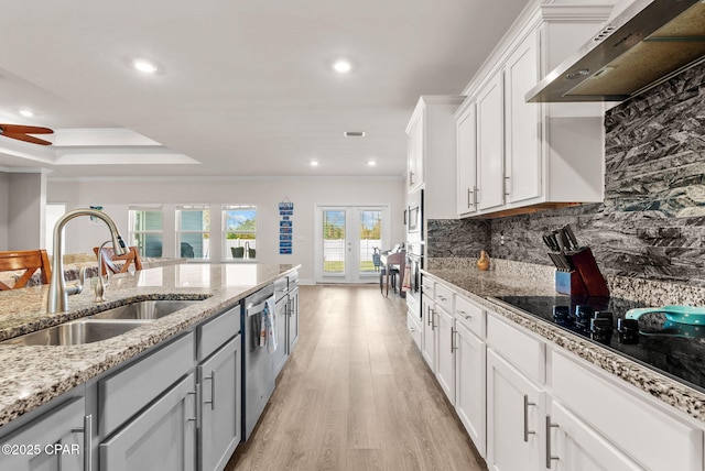 kitchen with light wood-type flooring, ornamental molding, a sink, decorative backsplash, and extractor fan