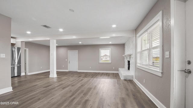 unfurnished living room with wood finished floors, recessed lighting, baseboards, and visible vents