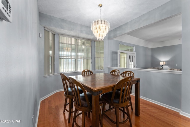 dining area with baseboards, a notable chandelier, and wood finished floors