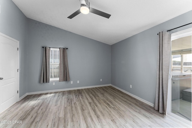 unfurnished room featuring lofted ceiling, wood finished floors, a ceiling fan, and baseboards