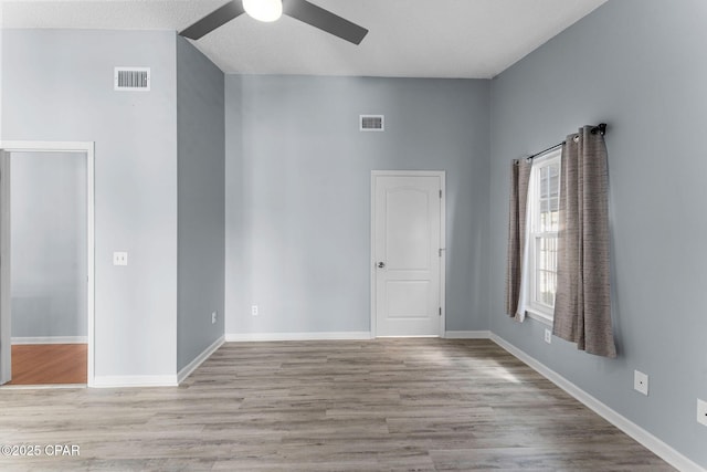 empty room with visible vents, baseboards, a ceiling fan, and wood finished floors