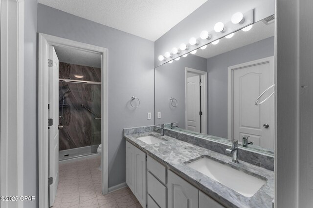 bathroom with a sink, a textured ceiling, marble finish floor, and a shower stall